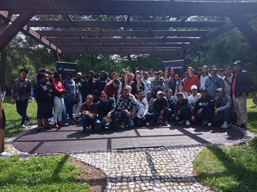 Workers gathered under a pergola at a Motives company event