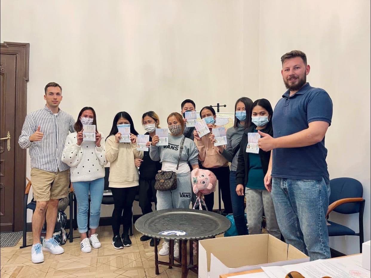 Twin Star applicants holding their residence permit cards, with agency staff
